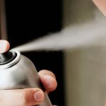 Mid section view of a young man spraying deodorant